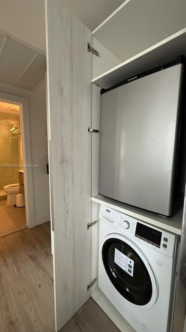 6080 Collins Ave Unit 402, Miami Beach, FL 33140 - clothes washing area with light wood finished floors and stacked washing machine and dryer