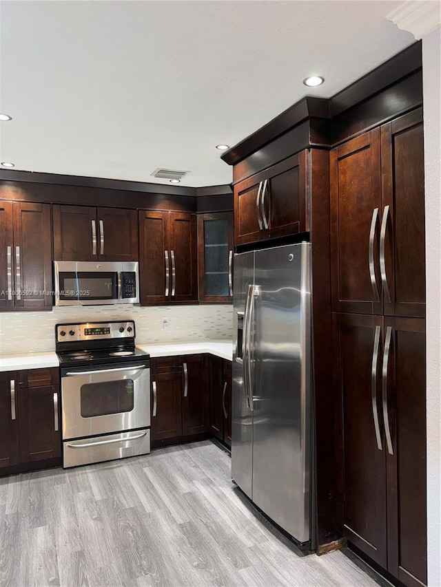 kitchen with stainless steel appliances, light countertops, light wood finished floors, dark brown cabinets, and recessed lighting