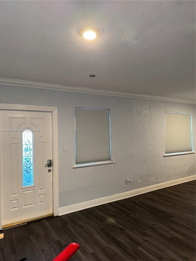 foyer with dark wood-style floors, ornamental molding, and baseboards