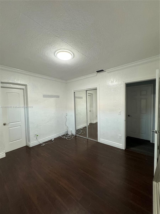unfurnished bedroom with crown molding, wood finished floors, a textured ceiling, a closet, and baseboards