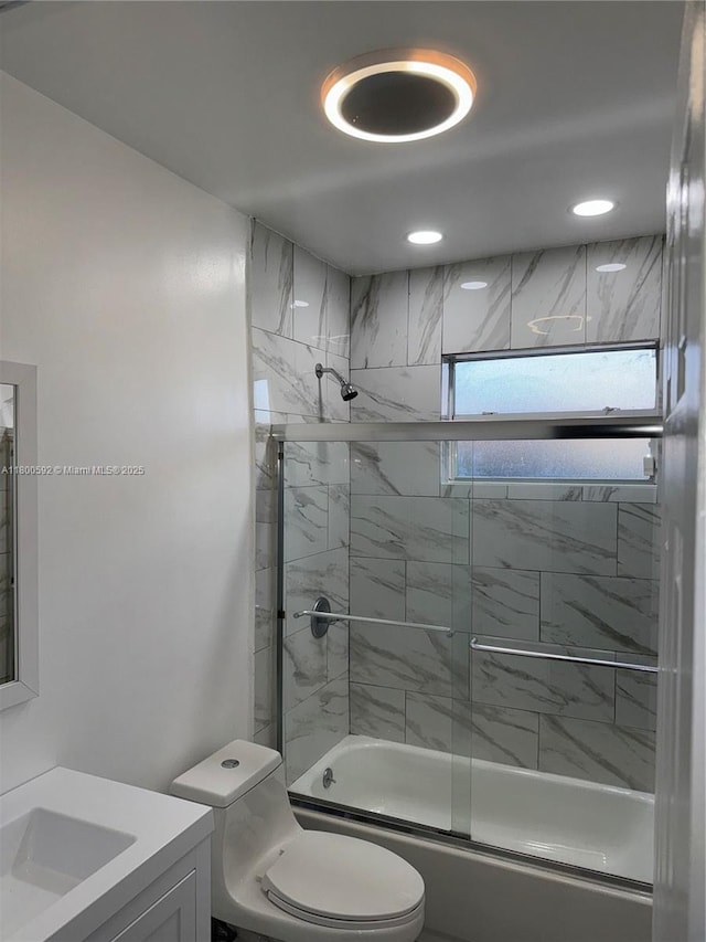 bathroom with toilet, combined bath / shower with glass door, and vanity