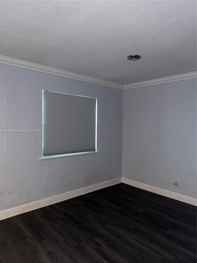 spare room with dark wood finished floors, baseboards, and crown molding