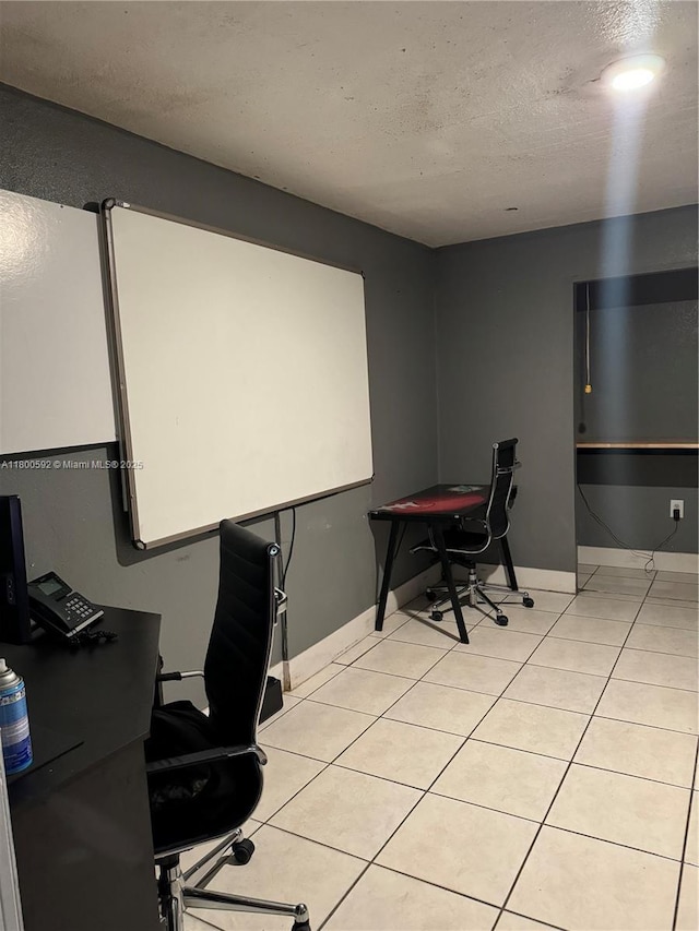 office featuring a textured ceiling, light tile patterned flooring, and baseboards