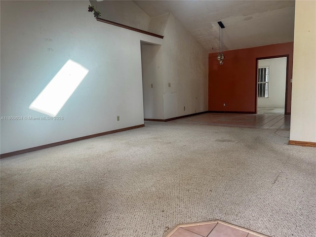 spare room with carpet floors, baseboards, and vaulted ceiling