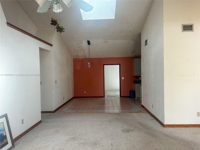 spare room featuring carpet floors, ceiling fan, baseboards, and a skylight