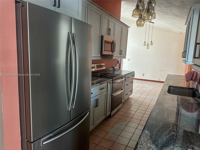 kitchen featuring appliances with stainless steel finishes, tile patterned floors, gray cabinetry, and dark stone counters
