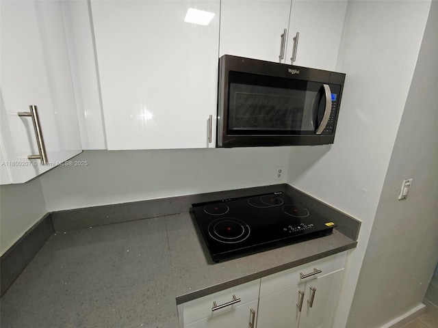 13500 NE 3rd Ct Unit 217, North Miami, FL 33161 - kitchen view of white cabinets, black electric cooktop, and dark countertops