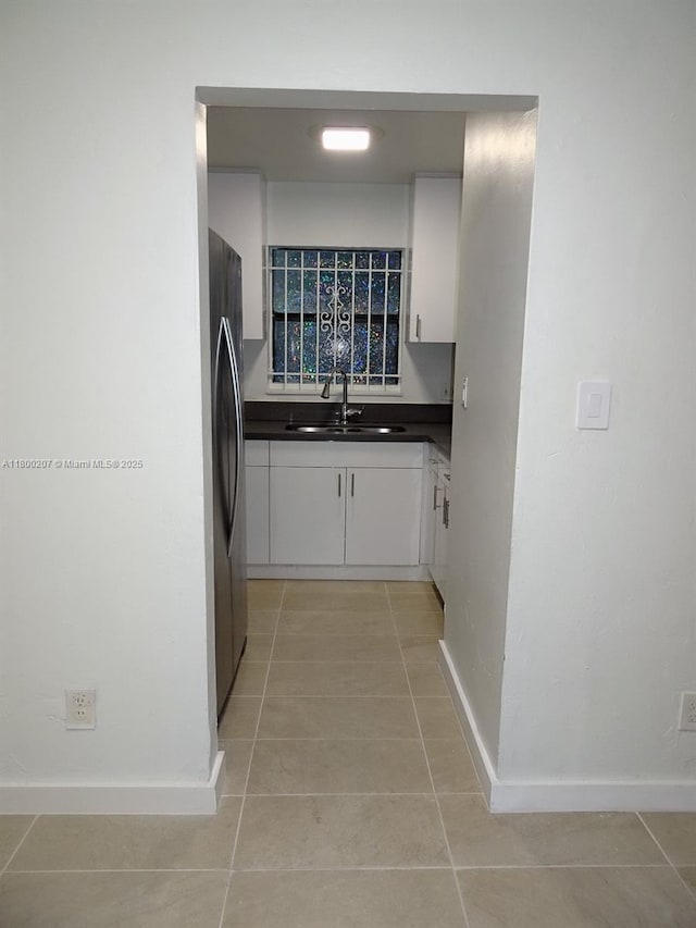 13500 NE 3rd Ct Unit 217, North Miami, FL 33161 - kitchen featuring dark countertops, light tile patterned flooring, white cabinetry, and freestanding refrigerator