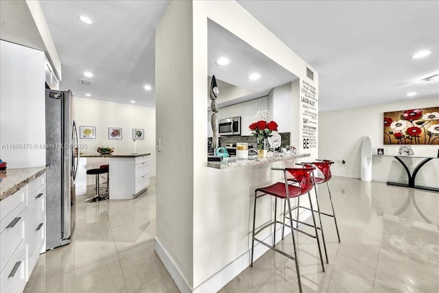 1060 SW 111th Way, Davie, FL 33324 - kitchen featuring stainless steel appliances, a breakfast bar, recessed lighting, white cabinets, and stone counters