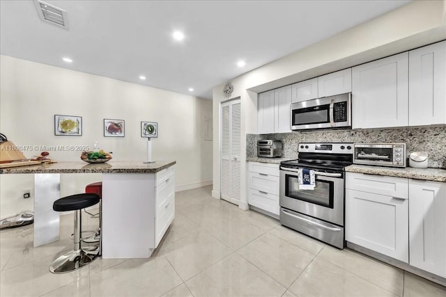 1060 SW 111th Way, Davie, FL 33324 - kitchen featuring stainless steel appliances, backsplash, light stone countertops, white cabinetry, and recessed lighting