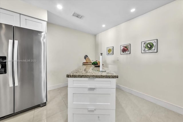 1060 SW 111th Way, Davie, FL 33324 - kitchen with stainless steel fridge, light tile patterned flooring, light stone countertops, white cabinets, and baseboards