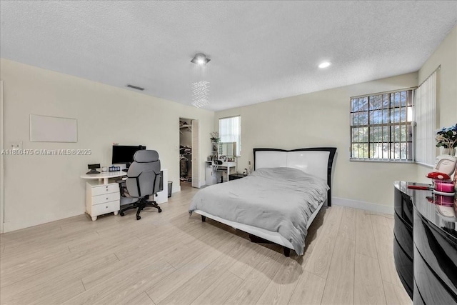 1060 SW 111th Way, Davie, FL 33324 - bedroom with a textured ceiling, light wood finished floors, a walk in closet, a desk, and baseboards