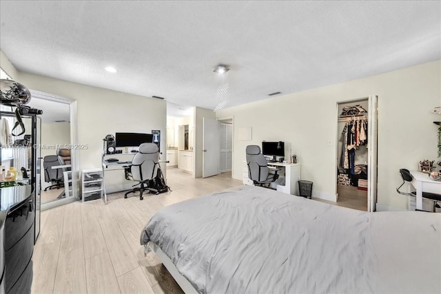 1060 SW 111th Way, Davie, FL 33324 - bedroom with a desk, light wood-style floors, a walk in closet, ensuite bathroom, and a textured ceiling