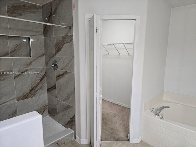 453 Dahoon Holly Dr, Daytona Beach, FL 32117 - bathroom with tiled shower, a bath, a walk in closet, and baseboards