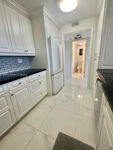 10777 W Sample Rd Unit 610, Coral Springs, FL 33065 - kitchen with freestanding refrigerator, light marble finish flooring, white cabinetry, dark countertops, and a textured ceiling