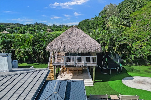 rear view of property with a trampoline, a gazebo, a patio area, view of scattered trees, and stairs