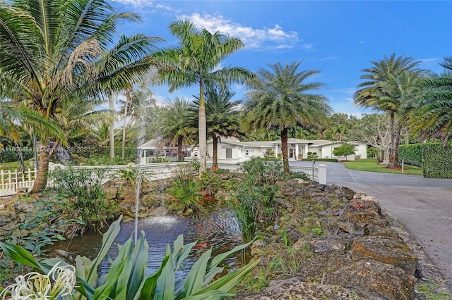 view of front of house with fence, a garden pond, and driveway