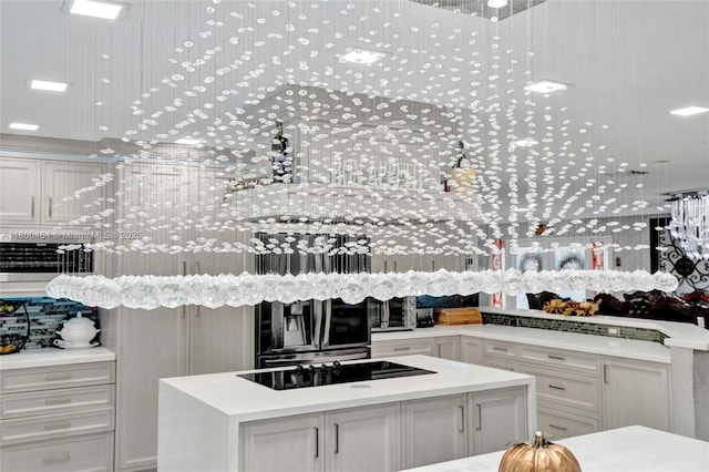 kitchen featuring a kitchen island, light countertops, black electric stovetop, and white cabinets
