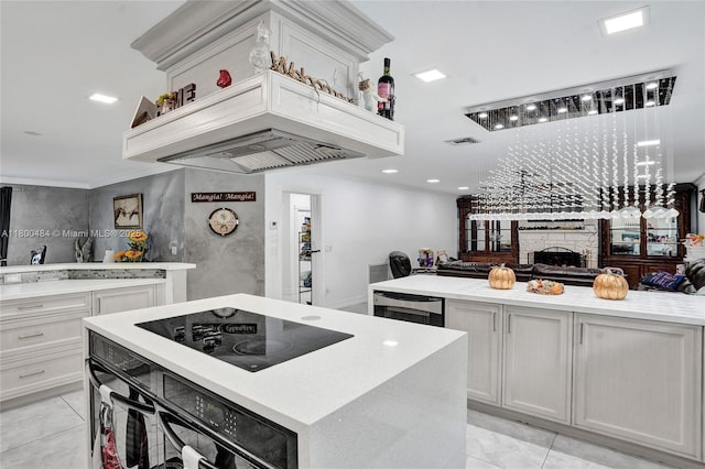 kitchen featuring black appliances, a kitchen island, a fireplace, light tile patterned flooring, and recessed lighting