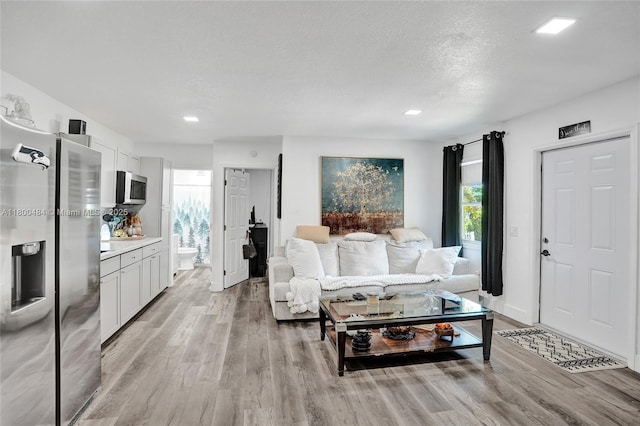 living area featuring light wood-style floors, recessed lighting, and a textured ceiling