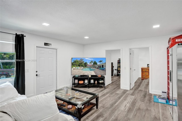 living area featuring light wood-style flooring, baseboards, recessed lighting, and a textured ceiling