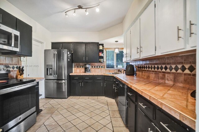 825 NE 98th St, Miami Shores, FL 33138 - kitchen with appliances with stainless steel finishes, dark cabinetry, white cabinetry, and decorative backsplash