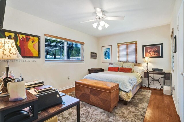 825 NE 98th St, Miami Shores, FL 33138 - bedroom featuring wood finished floors, baseboards, a wall unit AC, a ceiling fan, and an office area