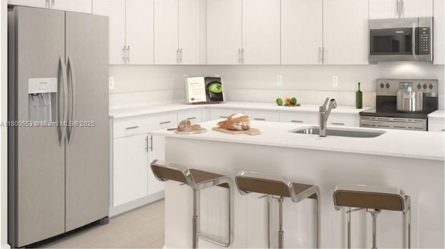 2332 NW 125th St Unit 2332, Miami, FL 33167 - kitchen featuring appliances with stainless steel finishes, a sink, a kitchen bar, light countertops, and white cabinetry