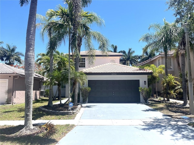 mediterranean / spanish house with stucco siding, a tiled roof, an attached garage, and concrete driveway