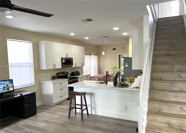 kitchen with stainless steel appliances, plenty of natural light, a breakfast bar area, light wood-type flooring, and recessed lighting