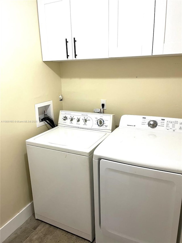 laundry room featuring cabinet space, separate washer and dryer, baseboards, and wood finished floors
