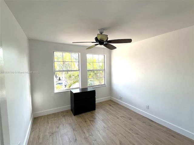 empty room with baseboards, light wood finished floors, and a ceiling fan