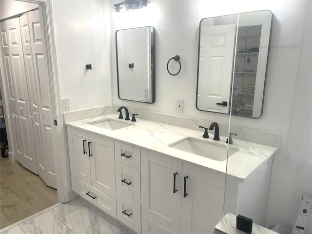 full bath featuring double vanity, marble finish floors, and a closet