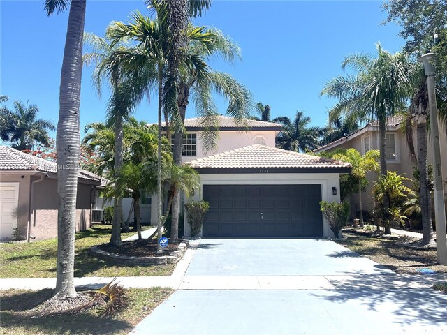 mediterranean / spanish-style home with stucco siding, a tile roof, a garage, and concrete driveway