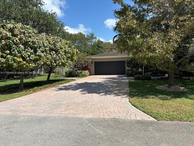 view of property hidden behind natural elements featuring decorative driveway, a front yard, a garage, and stucco siding