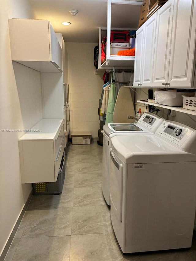 clothes washing area featuring cabinet space, separate washer and dryer, and baseboards