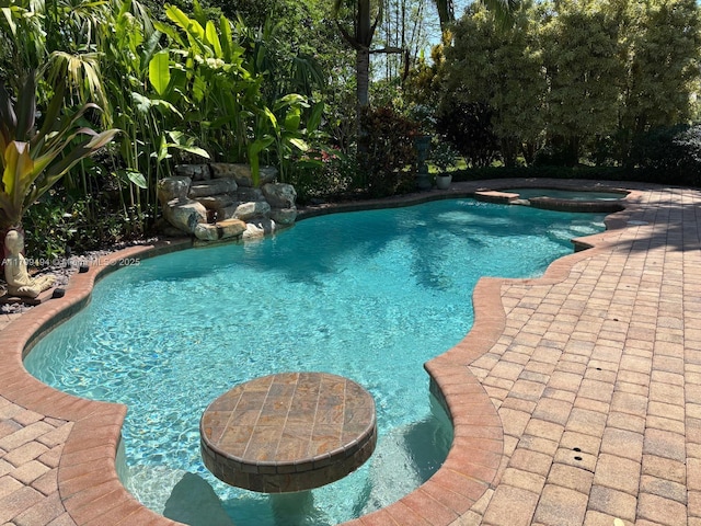 view of pool featuring a pool with connected hot tub and a patio area