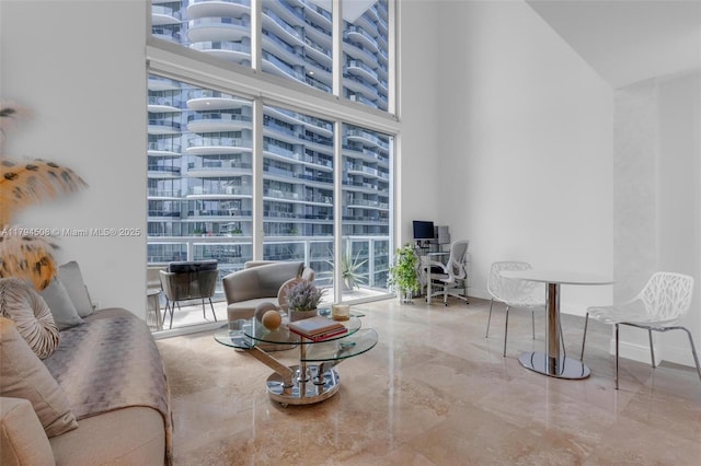 living room featuring a towering ceiling, an office area, and marble tiled floors