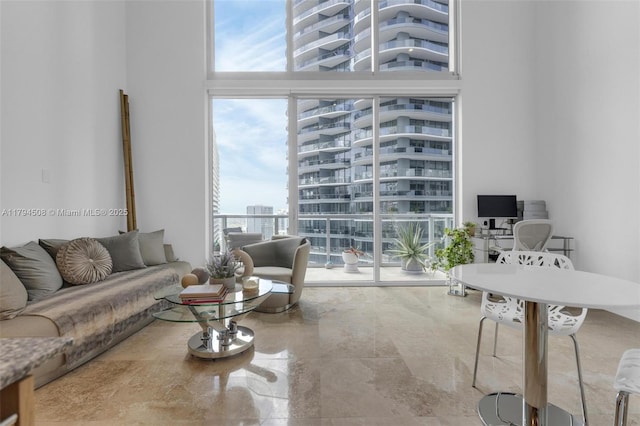 living area featuring a towering ceiling, an office area, and a wall of windows