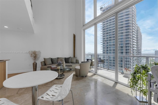 living area featuring a towering ceiling and baseboards