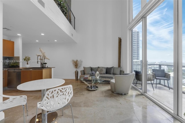 living room featuring healthy amount of natural light, a towering ceiling, baseboards, recessed lighting, and a view of city