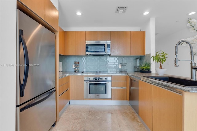 kitchen with stainless steel appliances, a sink, a peninsula, decorative backsplash, and recessed lighting