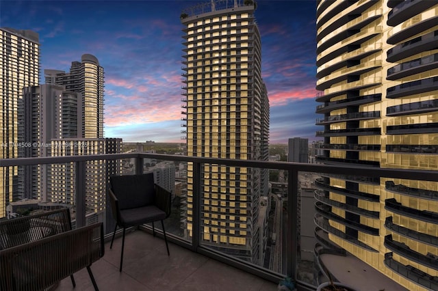 balcony at dusk featuring a city view