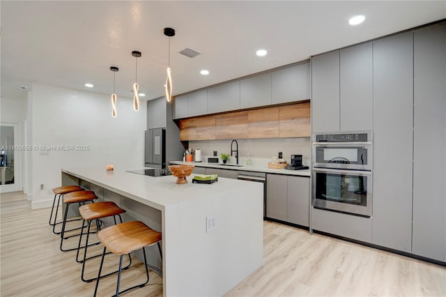 377 NE 34th Ter, Homestead, FL 33033 - kitchen featuring a sink, a breakfast bar, light wood finished floors, gray cabinets, and recessed lighting