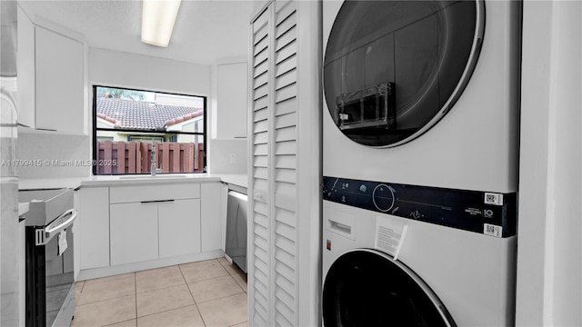 laundry area featuring estacked washer and dryer and light tile patterned floors