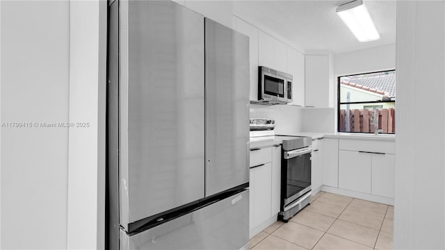 kitchen featuring stainless steel appliances, light countertops, white cabinetry, and light tile patterned floors