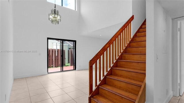 foyer entrance with a towering ceiling, stairs, healthy amount of natural light, a chandelier, and baseboards