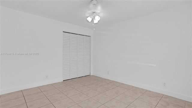spare room featuring light tile patterned floors, baseboards, and ceiling fan