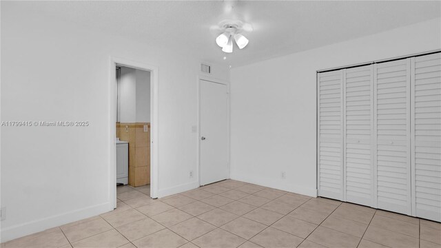 unfurnished bedroom featuring light tile patterned floors, a closet, and washer / dryer