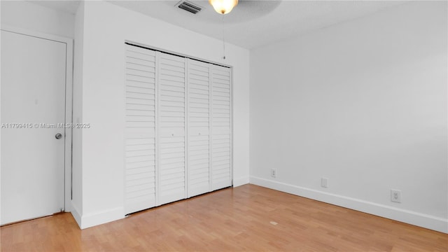 unfurnished bedroom featuring light wood finished floors, baseboards, a closet, and a ceiling fan